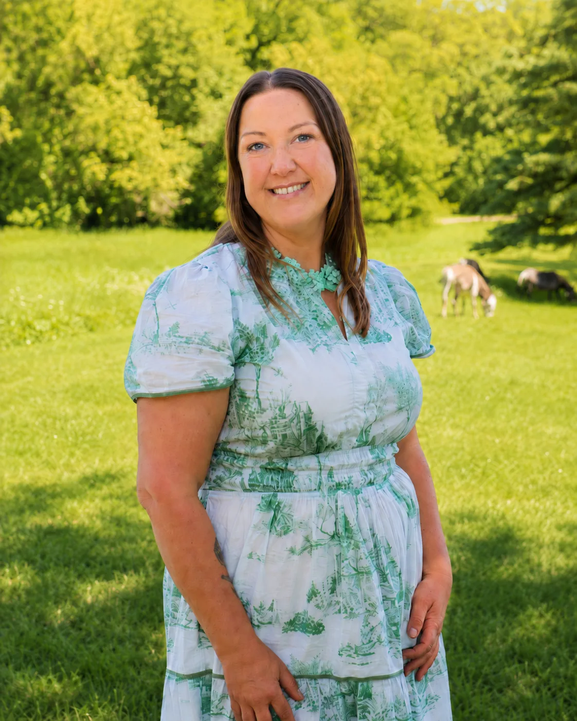 Lea Greene standing on her North Dakota farm, smiling in a green dress